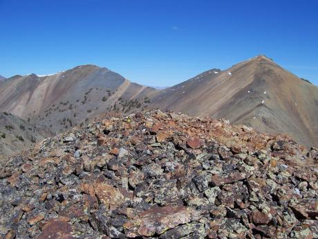 Pion and Eer Peaks, photo by Rick Baugher From the likely untrodden summit of Argosy Peak el 10377' the view is NE across the head of Argosy Creek. Pion 10680' is on the left. The 1934 GLO post is just to the right of this summit. Eer 10744' is the pointed peak on the far right. Note the multicolored rhyolite and andesite rockbands characteristic of this mineralized area. Motorists travelling US Highway 20/26/93 from Carey to Craters get a brief tantalizing view of this 3 peak cluster from Fish Creek opening. Photo date 9/28/06.